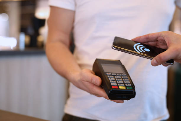 istock Man paying with mobile phone over pos terminal with nfc technology 1401239517