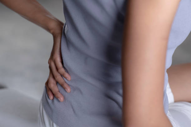 istock Woman sitting on bed and suffering from back pain. 1401241687