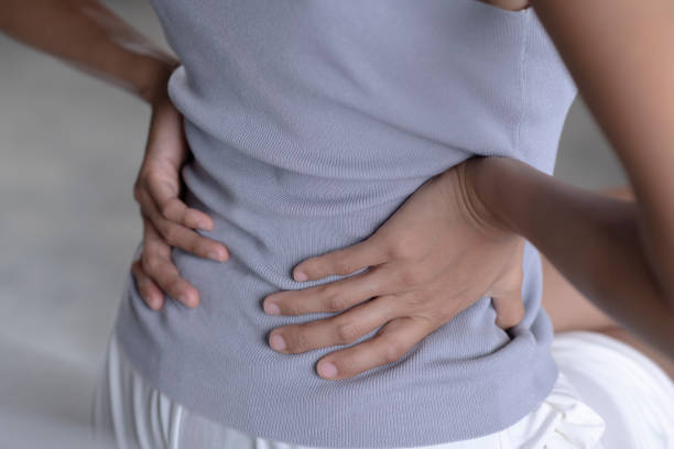 istock Woman sitting on bed and suffering from back pain. 1401241690