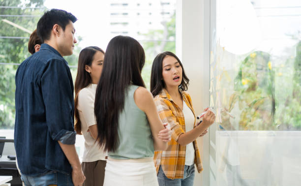 istock Asian business creative team meeting planning by using post-it notes to share ideas on a glass wall. 1401242494