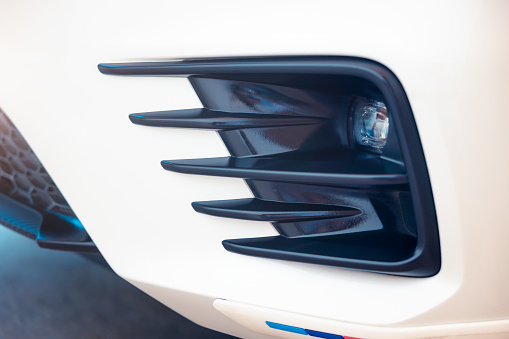 Close up detail of front fog lamp of auto car vehicle. Automotive lighting consist of white led bulb, round glass cover and bumper. System technology or equipment for security of transportation.