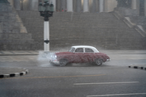 Old car making its way through a puddle as a result of the heavy rains that fall on the capital of the island of Cuba. Havana. Cuba January 4, 2020.