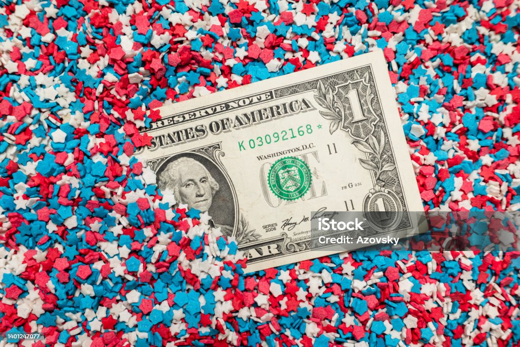 One dollar american bill One American dollar bill (money) is buried, close up. Texture of the colors of the American flag. Background of confectionery sprinkles in the form of colored asterisks or stars. Day Stock Photo
