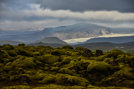 A moss-covered lava field and glacier covered mountains near Kirkjubaejarklaustur, south Iceland