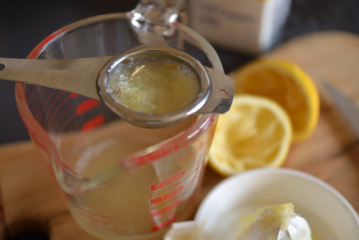 Straining the lemon juice into a jug to remove the seeds and pulp
