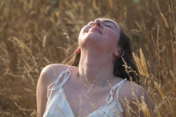 Young woman posing in a tall grassy field in the early evening.
