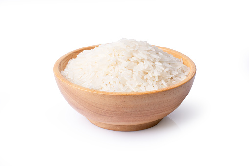 White uncooked long rice in wooden bowl isolated on white background with clipping path.
