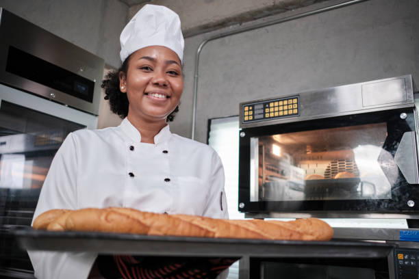 istock Professional female chef with baking bread, cheerful smile in the kitchen. 1401262166