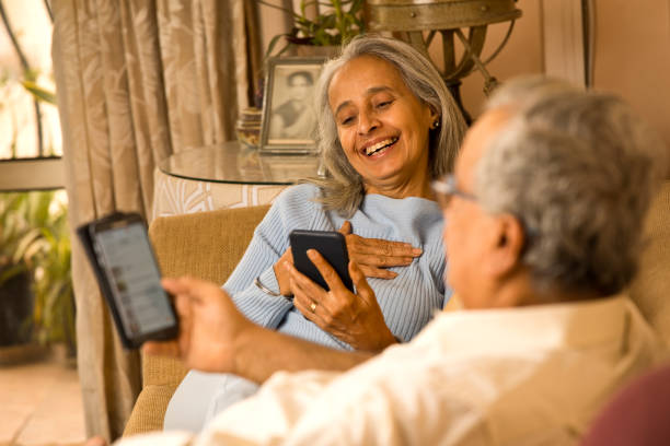 istock Old couple using mobile phones while relaxing on sofa at home 1401266164