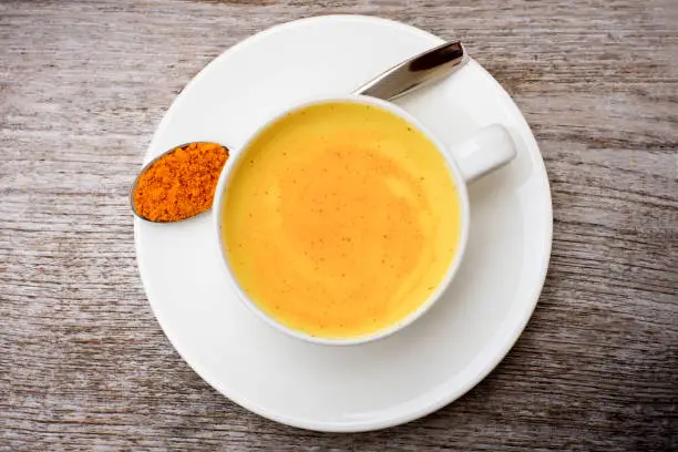 Turmeric milk with tumeric powder isolated on table background. Top view. Flat lay.