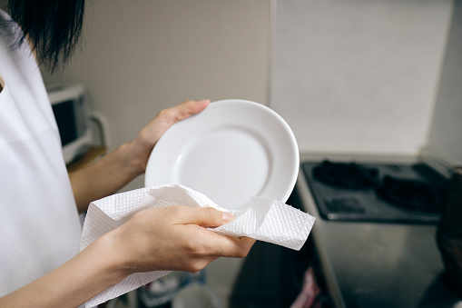 Closeup of woman's hands wiping dish