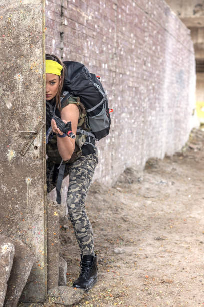 istock Young woman with gun in ruined old structure hide and look 1401268958
