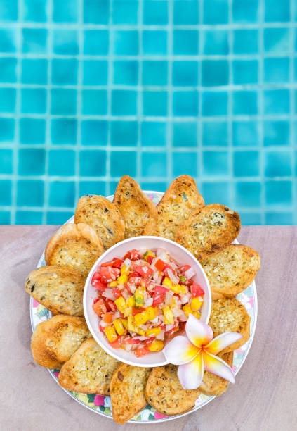 istock Homemade mango salsa with garlic bread with space on swimming pool edge background 1401271589