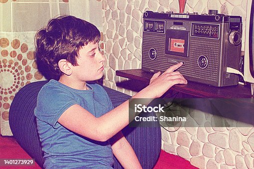 istock Vintage teenage-boy playing music on a radio cassette recorder 1401273929