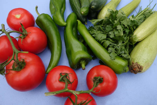 Mixed ripe vegetables placed on a kitchen table Tomatoes, zucchini, cucumber, green pepper and flat-leaf parsley