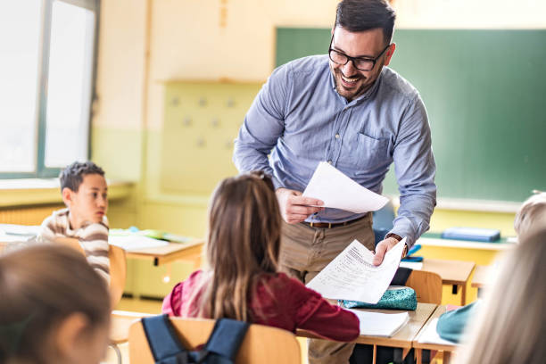 istock Happy teacher giving an exam paper to his student on a class. 1401277407