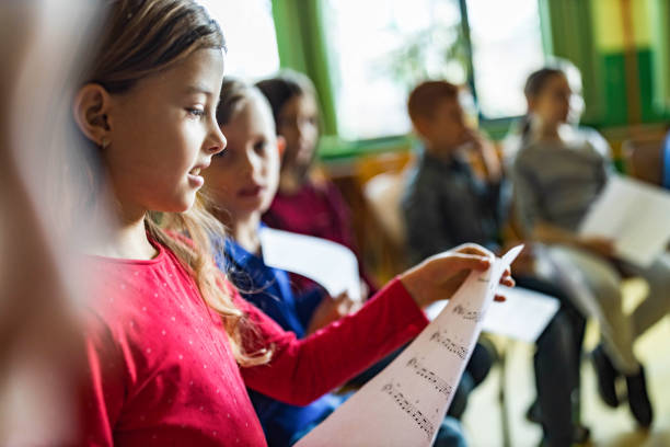 istock Schoolgirl practicing with sheet music on a class at school. 1401277427