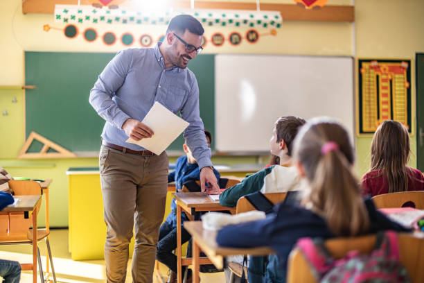 istock Happy male teacher assisting his student on a class at elementary school. 1401278102