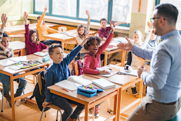 istock Large group of happy students raising hands to answer the teacher's question on a class. 1401278257