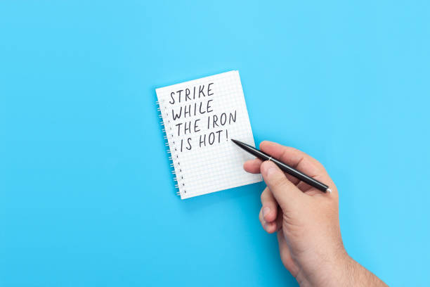 istock Hand with a pen writing in a notebook Strike while the Iron is hot 1401279306
