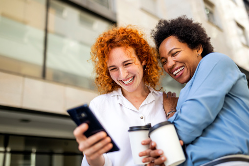 Mujeres sonrientes usando un teléfono inteligente en la ciudad photo