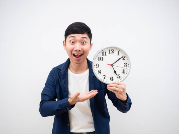azjata pokazuje zegar w dłoni szczęśliwa twarz zejść z pracy koncepcja na białym tle - clock wall clock face clock hand zdjęcia i obrazy z banku zdjęć