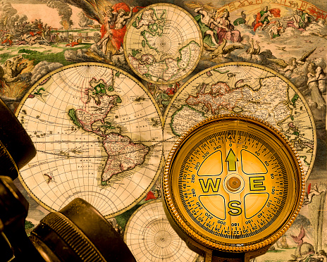 Old hand held compass on world map with binoculars. Focus in the centre.Stock Image.