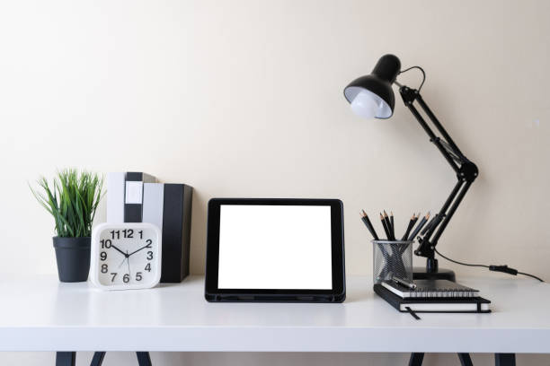 istock Modern contemporary workspace with mockup blank screen tablet computer and office supplies on white table. Front view of workplace space. Home office, work from home concept. 1401283083