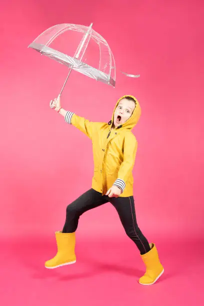 Photo of Happy little girl wearing raincoat and holding umbrella