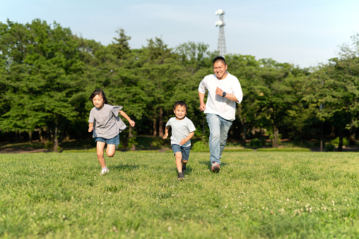 Father and two children running on lawn