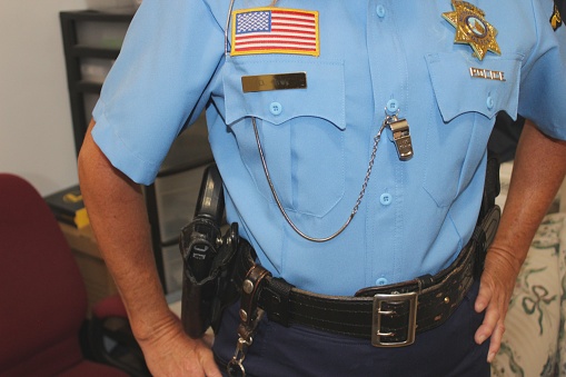 close up of uniform of police woman, blue in color, badge, gun belt