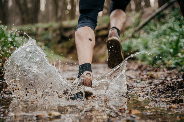 istock Close-up of athlete splashing water while running through stream at forest 1401285257