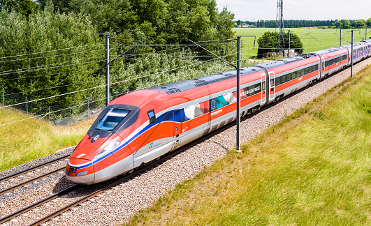 Chevry-Cossigny, France - June 1, 2022: A Frecciarossa (ETR 1000) high speed train from italian rail company Trenitalia is driving from Lyon to Paris on the LGV Sud-Est in the countryside.
