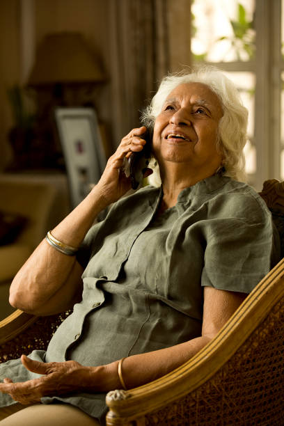 istock Old woman using mobile phone at home 1401285536