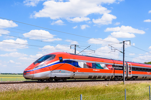 Chevry-Cossigny, France - June 1, 2022: A Frecciarossa (ETR 1000) high speed train from italian rail company Trenitalia is driving from Lyon to Paris on the LGV Sud-Est in the countryside.