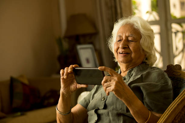 istock Old woman using mobile phone at home 1401286916