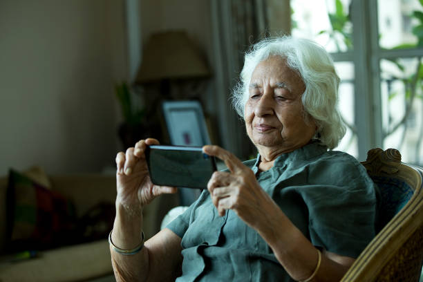 istock Old woman using mobile phone at home 1401286934