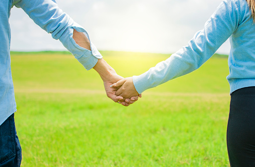 Hands together of a couple in the field, Close up of a couple holding hands, Concept of couple hands holding hands