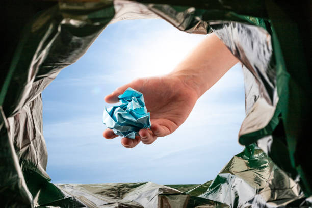 Recycling: Throwing paper in the trash bin stock photo
