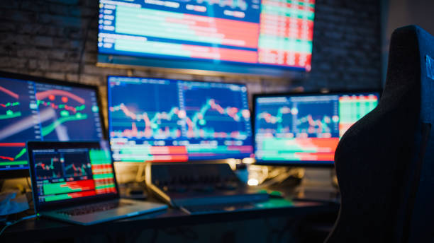 istock Laptop and computer screens with stock market graphs at desk 1401290587