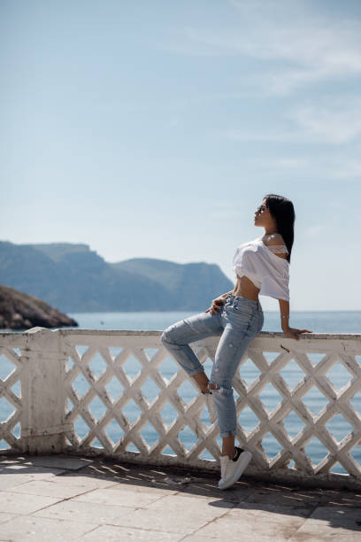 Summer portrait of a young brunette woman outdoors, spending time alone, by the calm sea in summer.