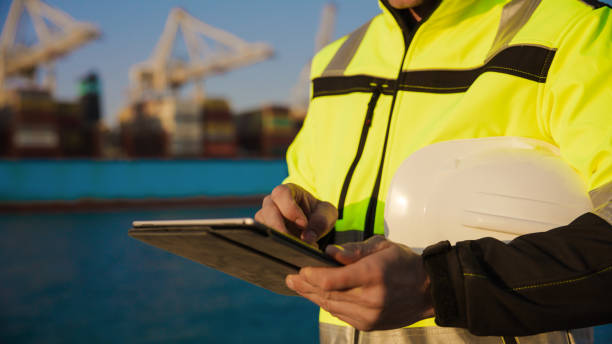 istock Man holding helmet and working on tablet computer in port terminal 1401294649