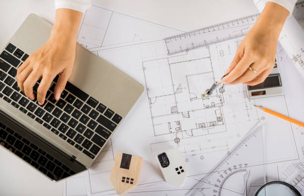 istock Architect typing laptop keyboard to review design of house before editing with compass 1401297014