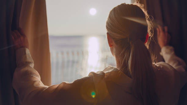 istock Woman opens window curtains on sea view window during sunset 1401297425