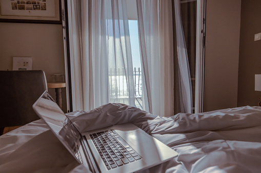 Laptop on bed in modern hotel bedroom