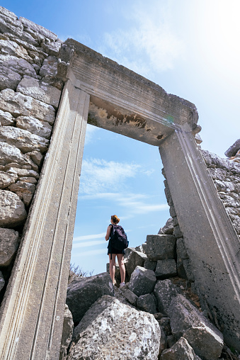 A woman climbing through the ruins of the ancient theater gate of the ancient city of Termessos.