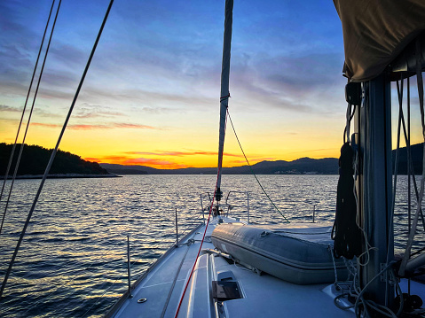 Yachts under sail and silhouette of setting sun on Tauranga harbor New Zealand