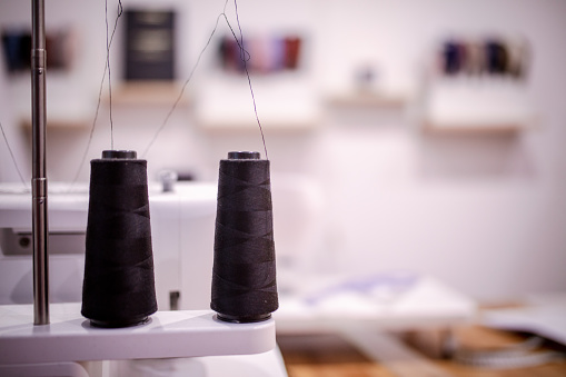 Close up of two black thread spindles fixed on a sewing machine