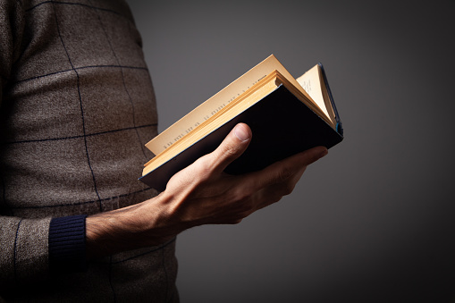 a man holding an old book on gray background