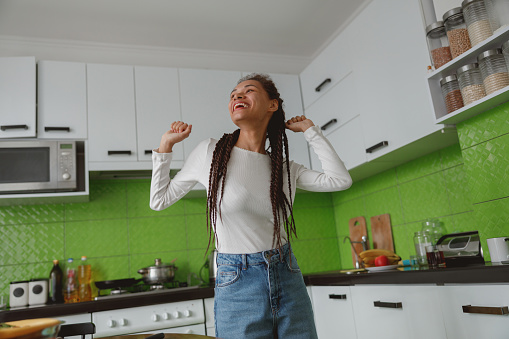 Bottom view of happy young female having fun at home dancing in the kitchen alone, leisure concept